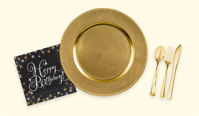 A gold round plate, an assortment of gold cultery and a black and gold napkin.