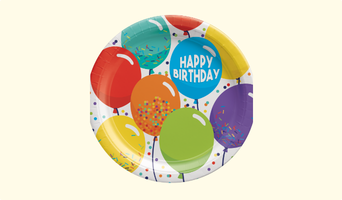 Une assiette en papier ronde avec les mots « Happy Birthday » imprimés sur un fond de ballons et de confettis multicolores.