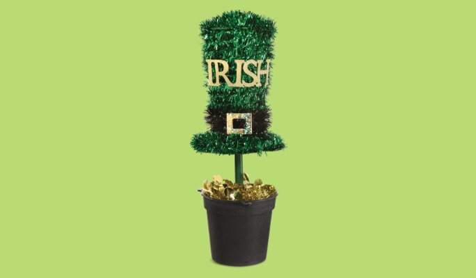 A green, black and gold tinsel top hat that reads "IRISH" on a stand, in a pot.