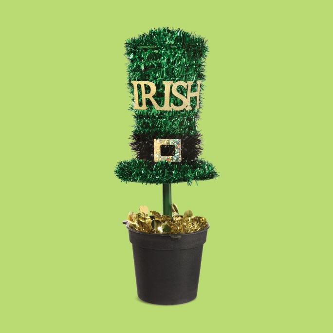 A green, black and gold tinsel top hat that reads "IRISH" on a stand, in a pot.
