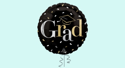 A round balloon with a black background, a gold outlined graduation cap, a "Grad" message and a silver, white and gold confetti pattern.