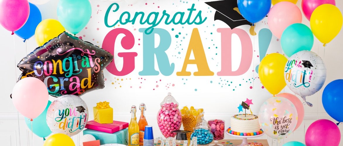 Bouquets of bright congratulatory graduation balloons, a table with gifts, treats & cake, and a banner that reads "Congrats GRAD!"