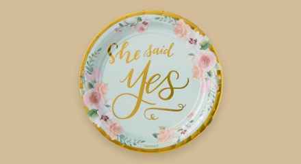 A mint green and floral-patterned plate that reads "She said yes".