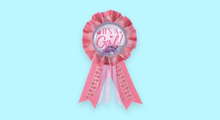 A pink ribbon pin that reads "IT'S A GIRL!"