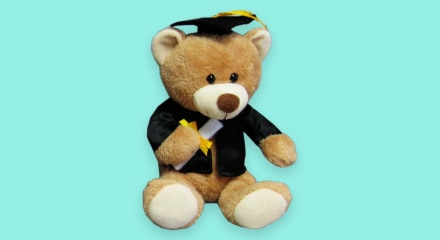 A teddy bear wearing a graduation cap and gown.