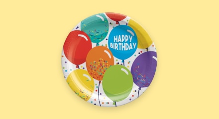Une assiette multicolore avec un motif de ballons et les mots « HAPPY BIRTHDAY ».