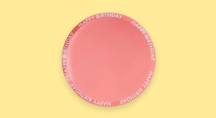 Une assiette rose avec les mots « HAPPY BIRTHDAY » autour de la bordure.