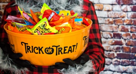 Halloween candy in an orange bucket that reads 'TRICK-OR-TREAT'.