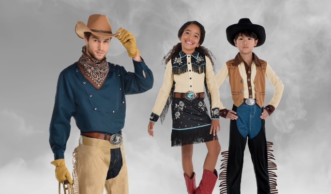 A young girl dressed as a cowgirl, a boy and a man dressed as cowboys.