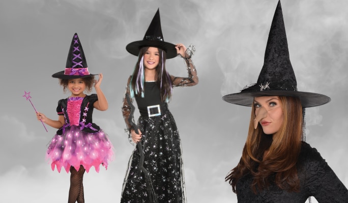 A woman and two girls wearing assorted witches’ costumes, wigs and accessories.