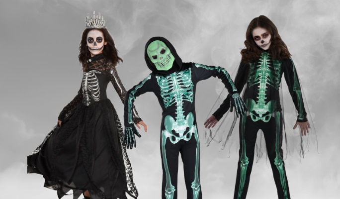 Three people wearing assorted skeleton costumes.