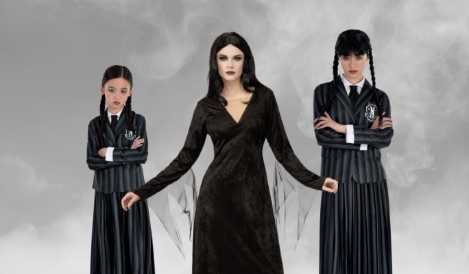 Three people wearing Morticia and Wednesday Addams costumes.