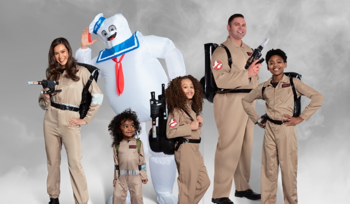 Three children and two adults in Ghostbusters costumes and an adult wearing an inflatable Stay Puft costume. 