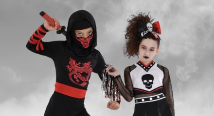  One kid wearing a ninja costume and one kid dressed as a zombie cheerleader.