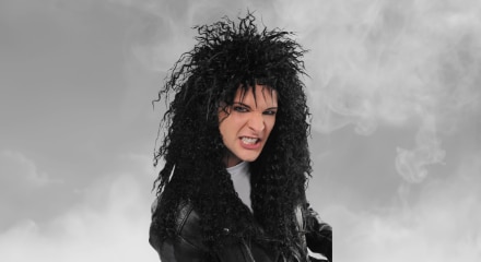 A man wearing a dark, crimped rock and roll wig.