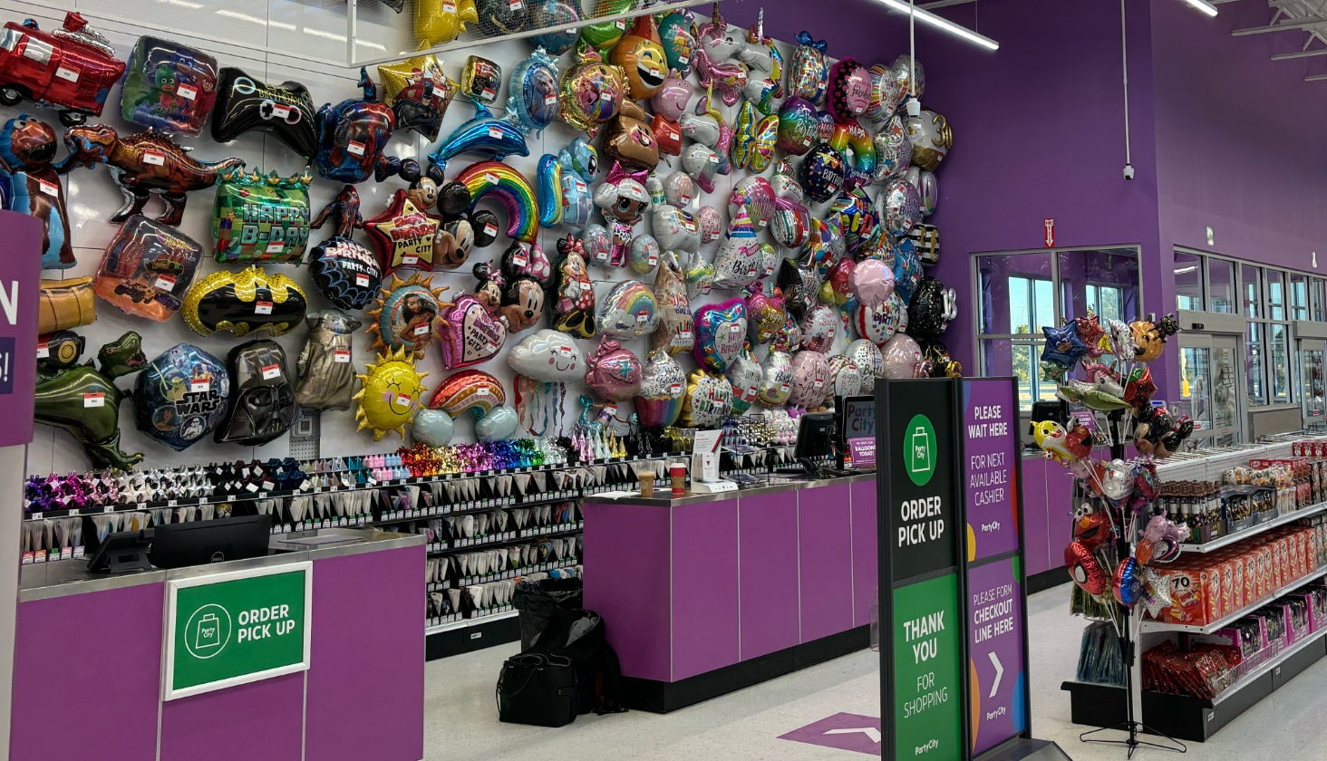 An employee handing a child a balloon at the custom balloon bouquet pick up counter.