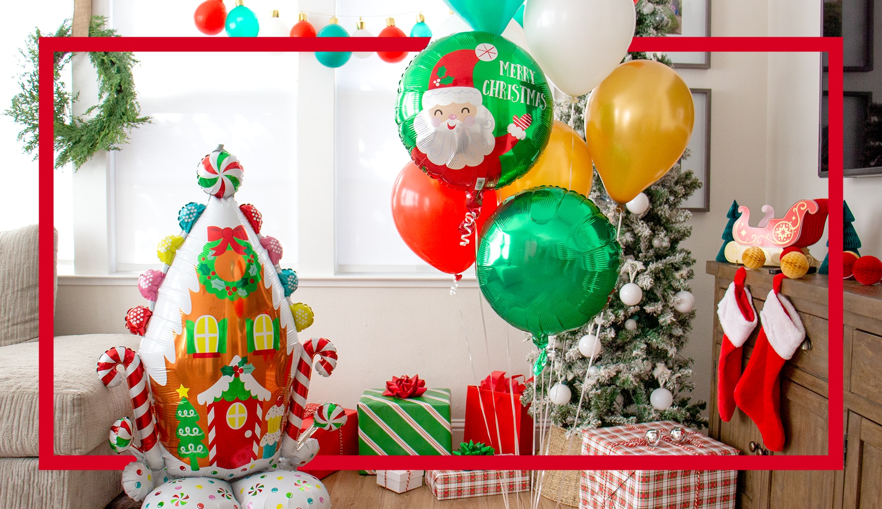 Un ballon en forme de maison en pain d’épices dans une pièce avec d’autres ballons de couleur Noël, des cadeaux de Noël et des bas rouges et blancs.