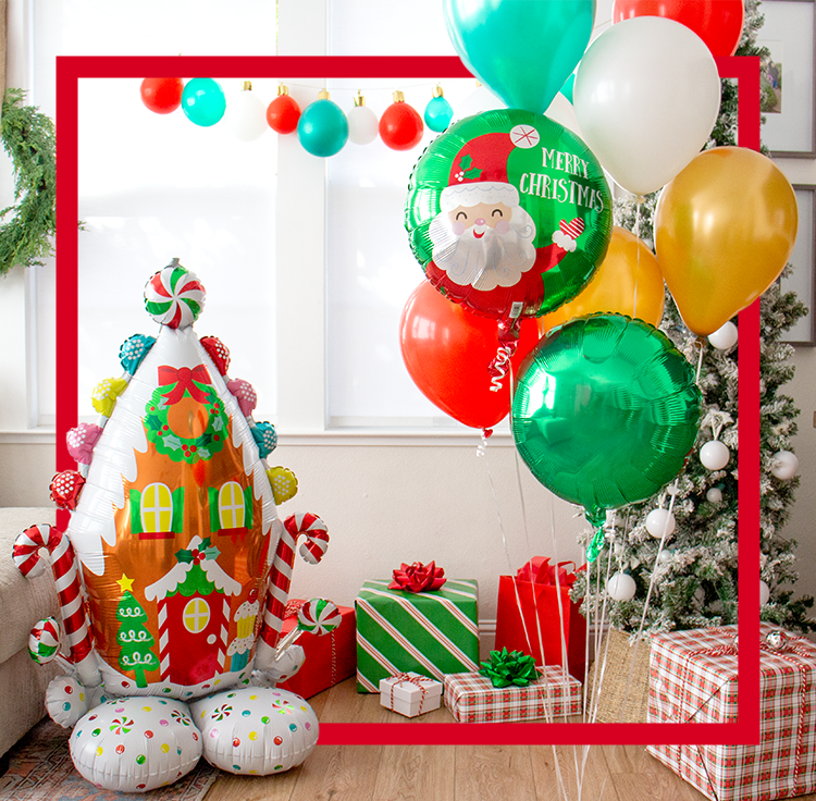 Un ballon en forme de maison en pain d’épices dans une pièce avec d’autres ballons de couleur Noël, des cadeaux de Noël et des bas rouges et blancs.