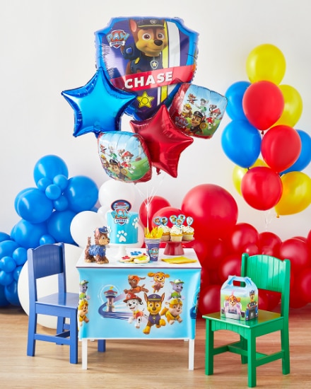 Des bouquets de ballons Pat’ Patrouille autour d’une petite table et des chaises décorées avec des décorations Pat’ Patrouille.