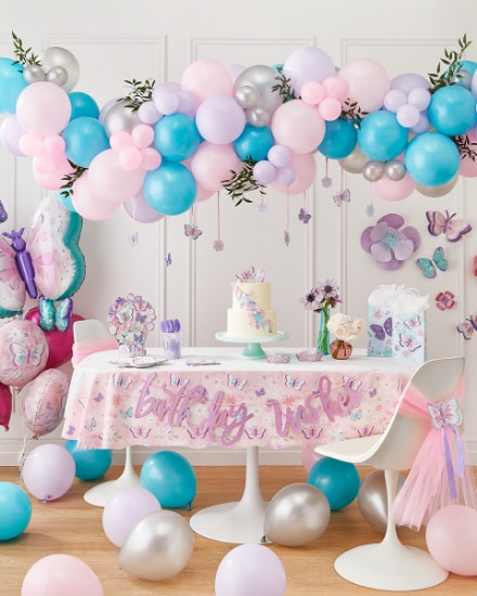 Une salle décorée avec des décorations, des ballons et de la vaisselle à thème de papillons.