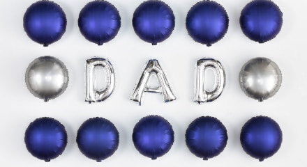 Silver helium-filled letter balloons that spell the word dad surrounded by round, navy blue foil balloons.