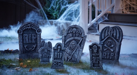 A lawn decorated for Halloween with cobwebs, fog and stone tombstones with the word RIP on the front.