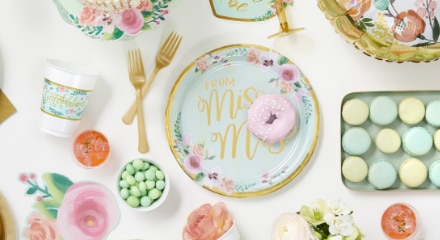 Pastel green and floral-themed wedding table decorations with  napkins, cups and plates that read 'From Miss to Mrs.' on the front.