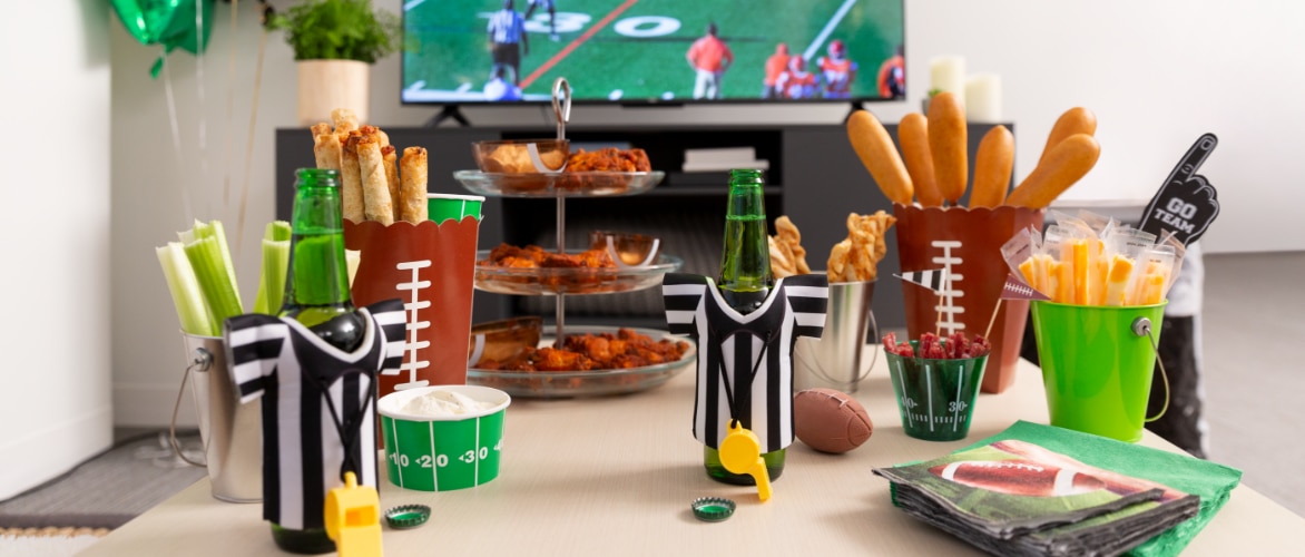 Game day food spread with referee jersey-shaped koozies and football napkins. 