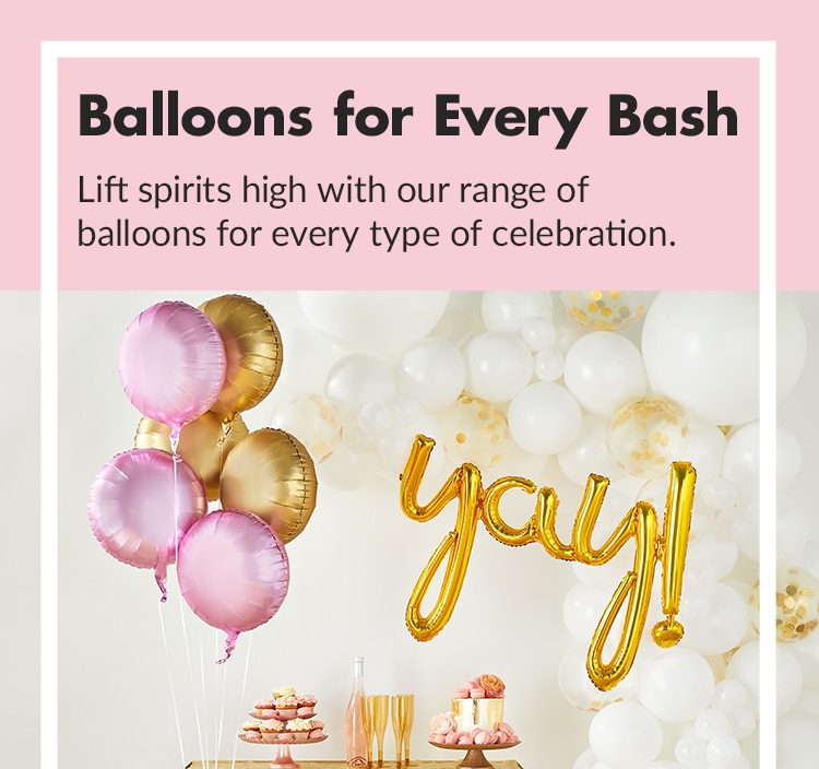 A tray of macarons and pink champagne next to pink and gold satin foil balloons, a balloon arch and ballons spelling "Yay."