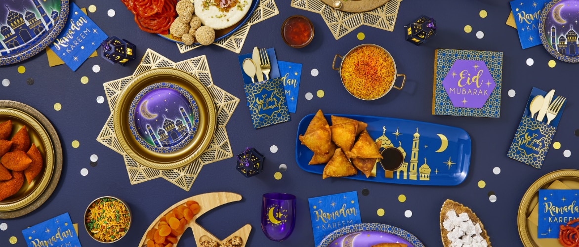 Tablescape featuring blue and gold paper plates and "Eid Mubarak" napkins.