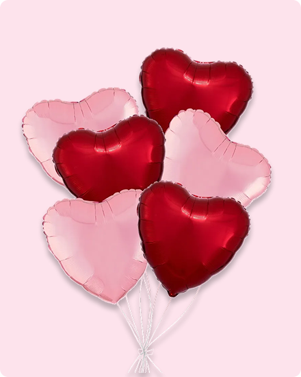 Six ballons rouges et roses en forme de cœur dans un bouquet de ballons.