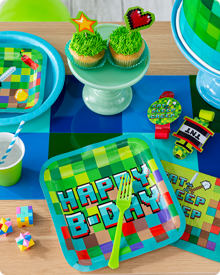 Une table décorée de petits gâteaux, de vaisselle, d’articles de service et de cadeaux-surprises à thème Minecraft.