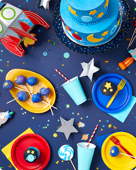 Une table bleu marine décorée d’étoiles, de couleurs primaires, de vaisselle, de plats de service et de collations de fête.