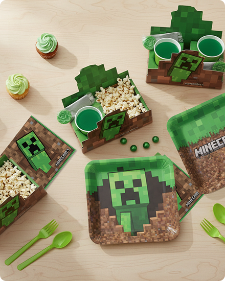 Une table décorée de petits gâteaux, de vaisselle, d’articles de service et de cadeaux-surprises à thème Minecraft.