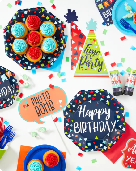 Une table bleu marine décorée d’étoiles, de couleurs primaires, de vaisselle, de plats de service et de collations de fête.